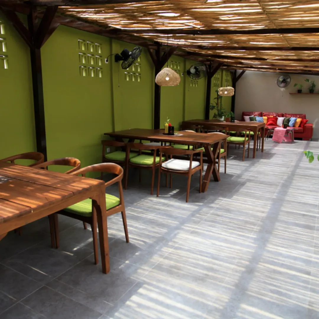 Area outdoor 5oUs Steakhouse dengan kursi kayu dan dinding hijau sage